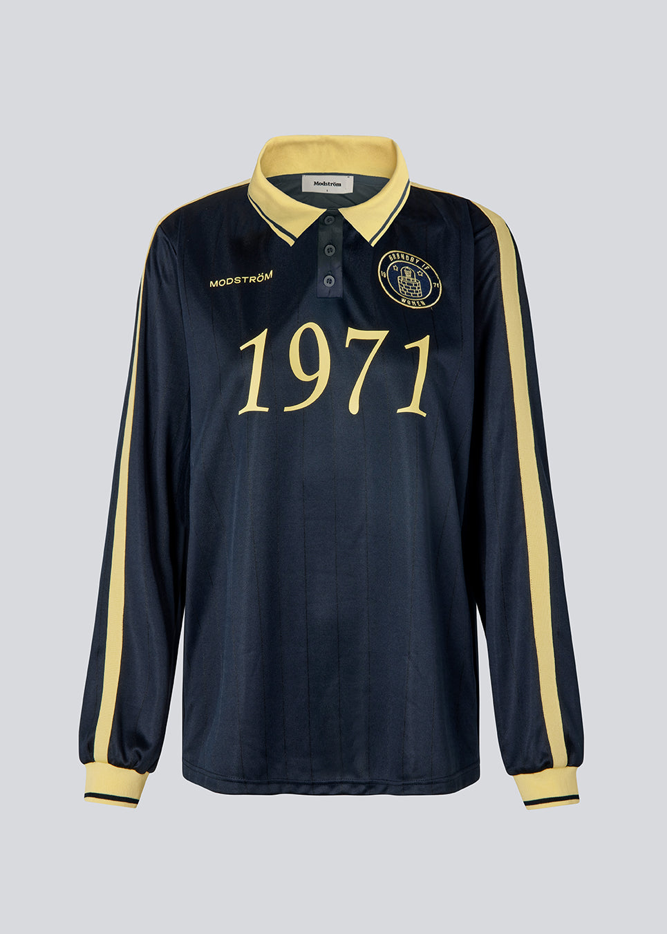 Football jersey made in collaboration with the Danish football team Brøndby Women. The 1971 Polo in navy with yellow details features a loose fit, with a placket closure and collar, as well as long sleeves that have ribbed cuffs. The polo features Brøndby Women and Modström logos on the chest.