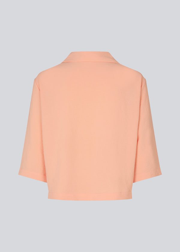 Shirt in the color Peach Necrar in a relaxed silhouette and 3/4 length sleeves. AaliyahMD shirt has a resort collar, dropped shoulders and button closure in front.