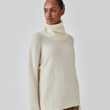 Oversized knitted jumper in white in wool and llama wool mix. AdrianMD t-neck has a relaxed fit with dropped shoulder, rib-knitted rollneck and trimmings. The model is 177 cm and wears a size S/36.