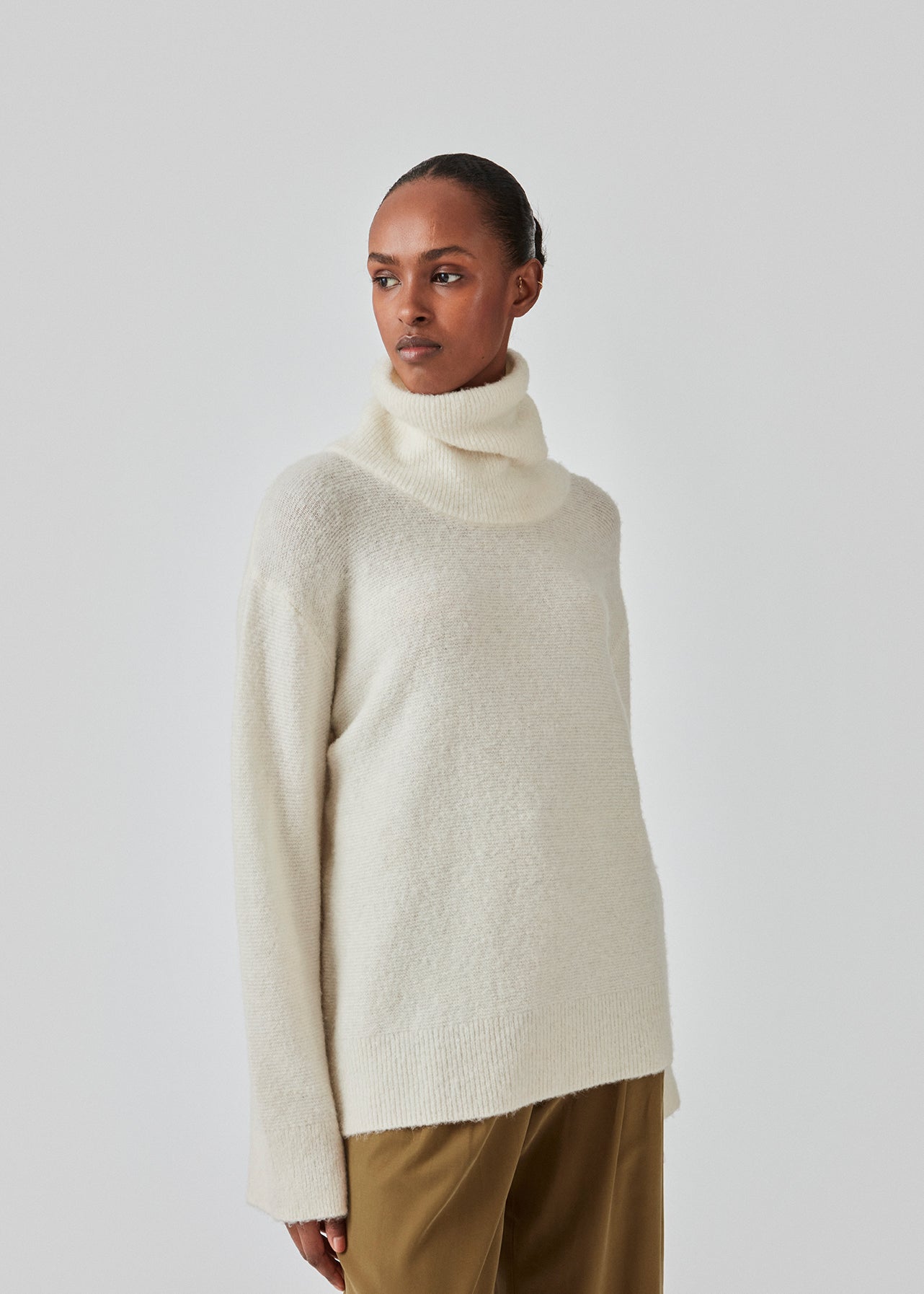 Oversized knitted jumper in white in wool and llama wool mix. AdrianMD t-neck has a relaxed fit with dropped shoulder, rib-knitted rollneck and trimmings. The model is 177 cm and wears a size S/36.