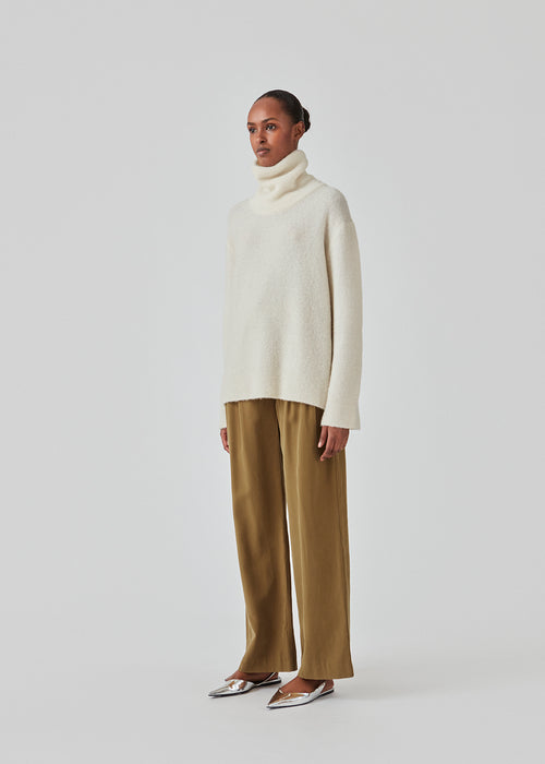 Oversized knitted jumper in white in wool and llama wool mix. AdrianMD t-neck has a relaxed fit with dropped shoulder, rib-knitted rollneck and trimmings. The model is 177 cm and wears a size S/36.