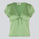 Feminine short-sleeve top in lustrous satin. The AijaMD Top features delicate details such as lace trims, a V-neckline, slight puff under the bust, and a bow detail. Made from 100% recycled polyester, perfect for both elegant and casual looks.