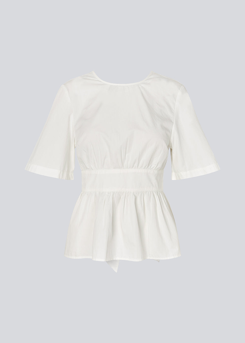 Feminine top with an open back and tie detail. The AikaMD Top features short sleeves, a round neckline, an A-line hem with pleating, and an attached band that cinches at the waist and ties at the back. The top is made from 100% organic cotton.