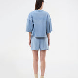 Light short-sleeve shirt in cotton denim. The AlvarMD Shirt is short and relaxed with a collar, V-neckline, and button closure. A casual and modern shirt, perfect for both everyday wear and light summer looks.