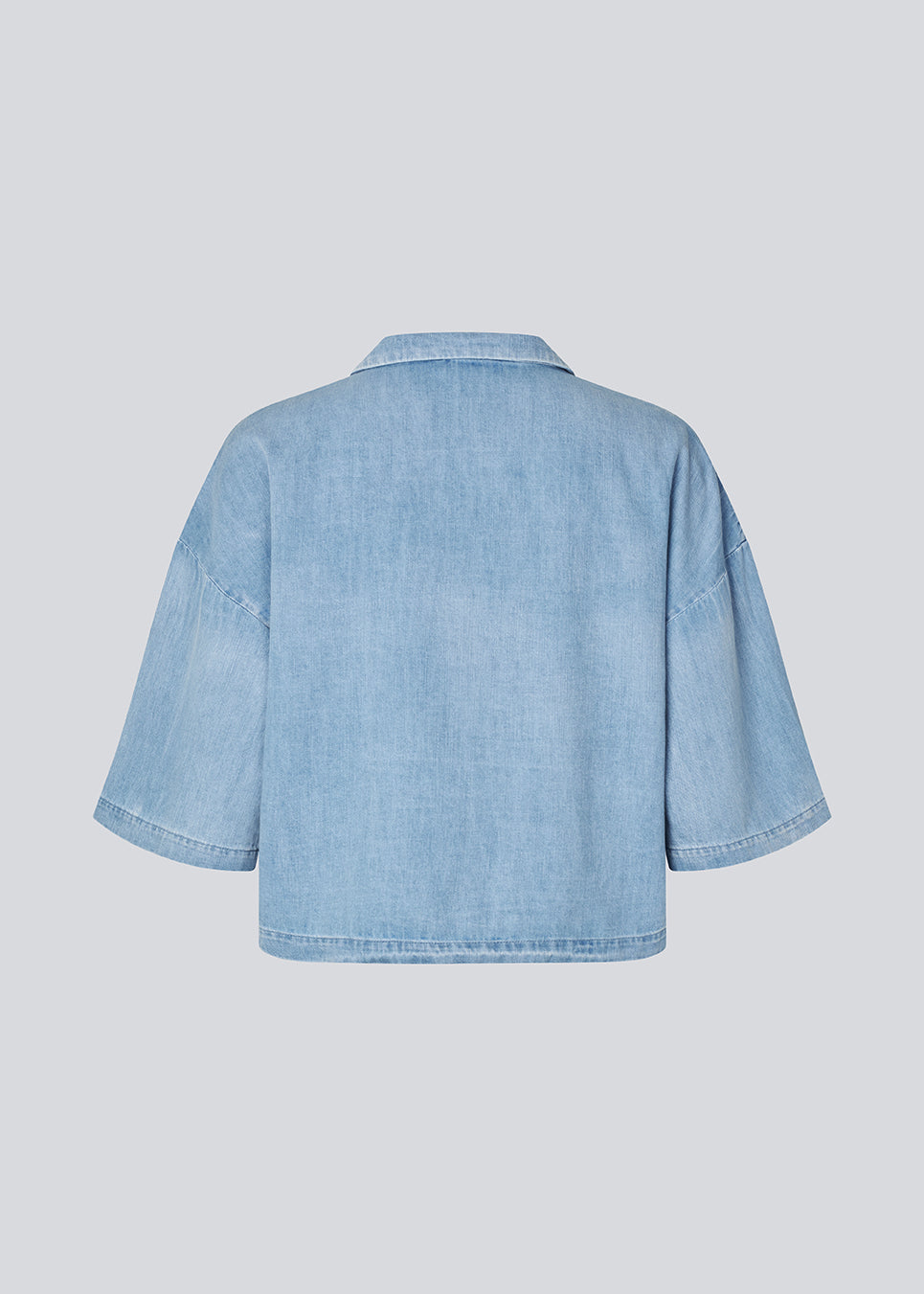 Light short-sleeve shirt in cotton denim. The AlvarMD Shirt is short and relaxed with a collar, V-neckline, and button closure. A casual and modern shirt, perfect for both everyday wear and light summer looks.