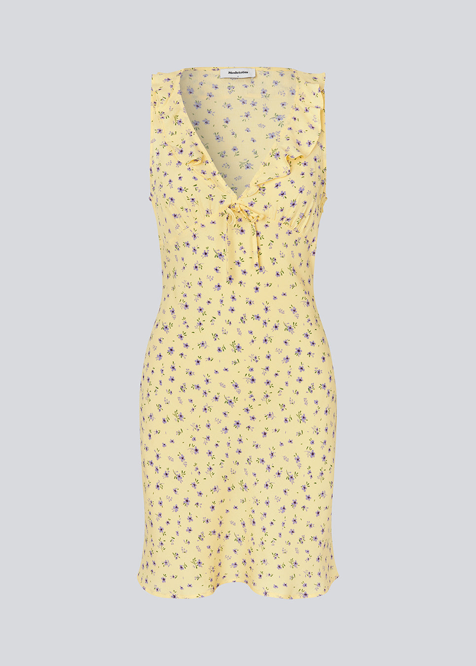Feminine mini dress with a summery floral print. The AlyssaMD Print Dress is sleeveless and features a V-neckline with a ruffle trim and bow detail. The dress is fitted at the waist and has a beautifully flowing skirt, creating a feminine and elegant look.