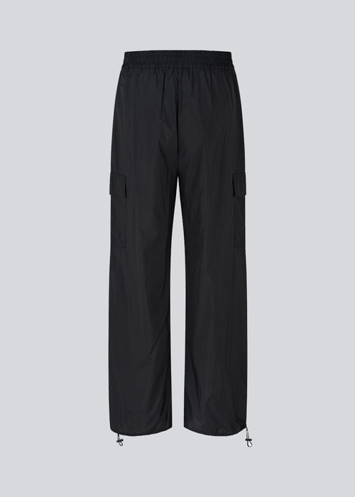 Black pants in recycled nylon. AmayaMD pants have a high waist and straight legs with adjustable drawstring at hem. Covered elasticated waist and two large pockets on the legs.
