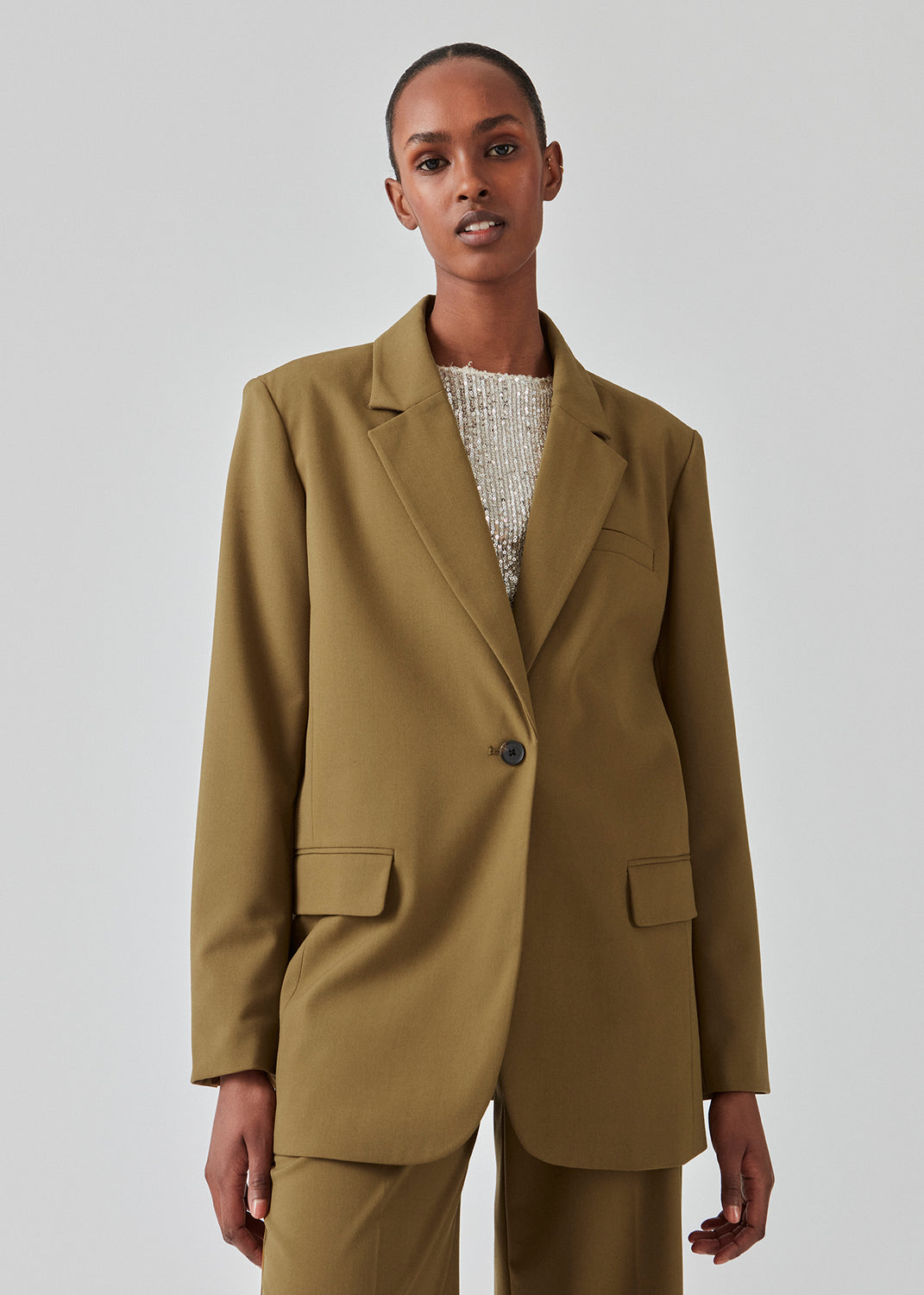 Oversized blazer with a drapy fit. AnkerMD blazer has collar and notch lapels with a single button closure. Flap welt front pockets. Slits on cuffs and single back vent. Lined.  The model is 177 cm and wears a size S/36. Style the blazer with matching pants in the same color: AnkerMD pants