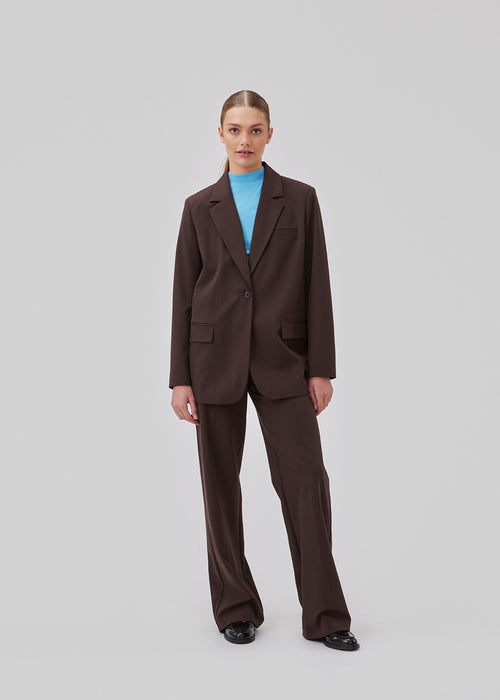 Pants in dark brown with wide legs and a medium waist. AnkerMD pants have creases, button and zip fly, side pockets and paspel back pockets. The model is 177 cm and wears a size S/36.