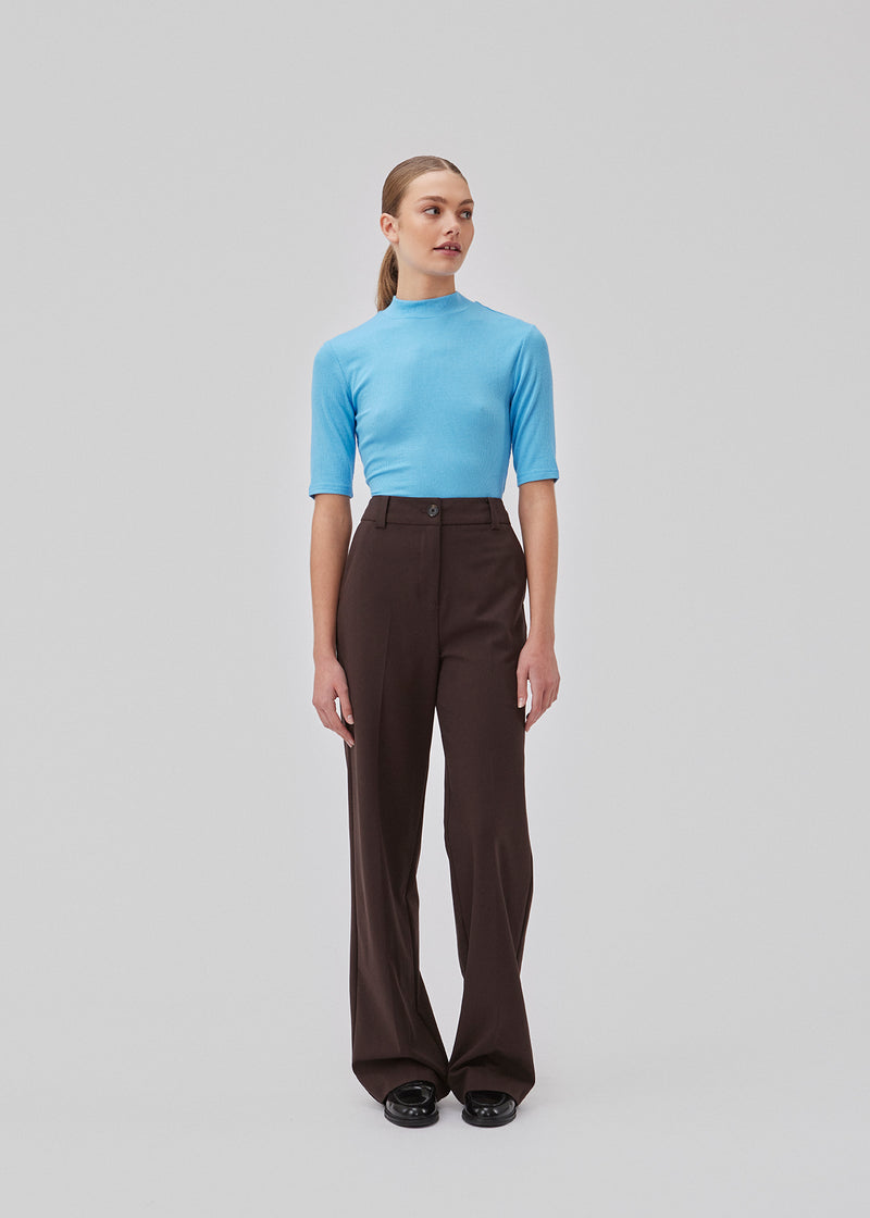 Pants in dark brown with wide legs and a medium waist. AnkerMD pants have creases, button and zip fly, side pockets and paspel back pockets. The model is 177 cm and wears a size S/36.