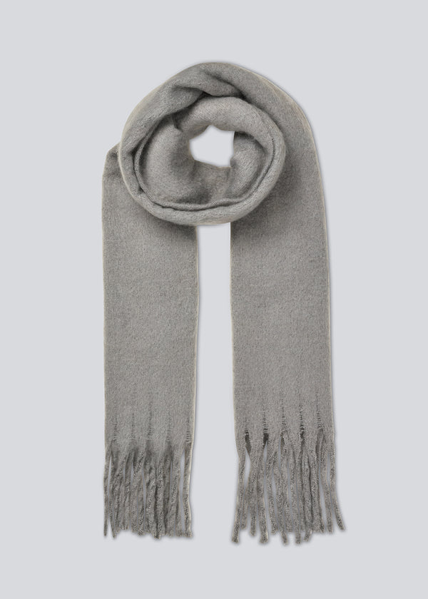 Oversized and snug scarf in a grey color with brushed finish with fringes along the shorter sides.