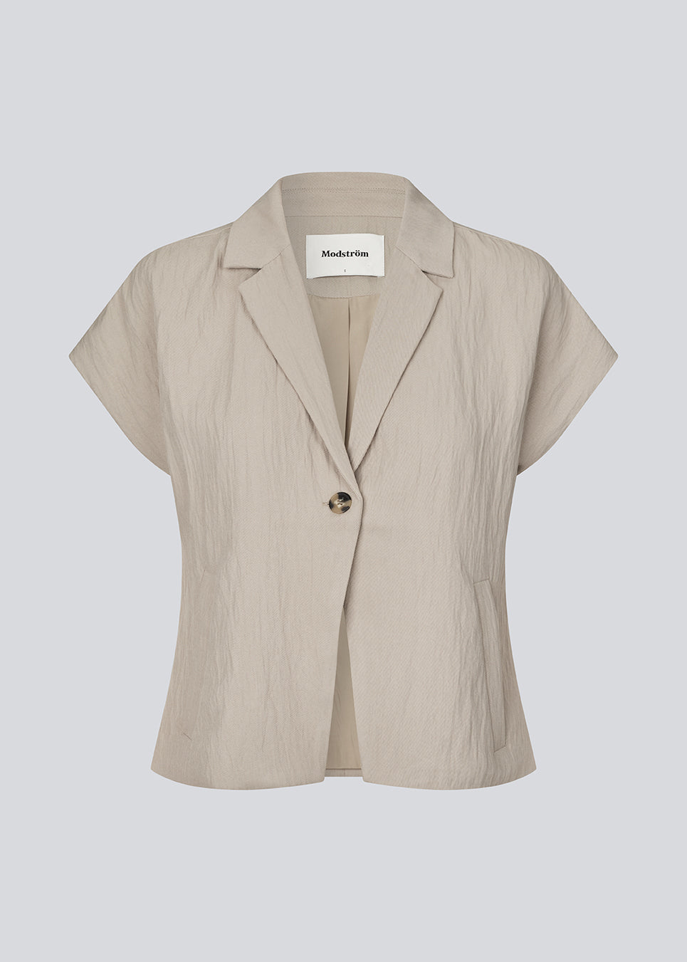 Short-sleeved blazer vest with a notched collar. The BenittaMD Vest features a relaxed, waist-focused fit, side pockets, and a single-button closure – the lightweight fabric creates a modern, effortless look, perfect worn alone or layered for a sharp, fashion-forward style.