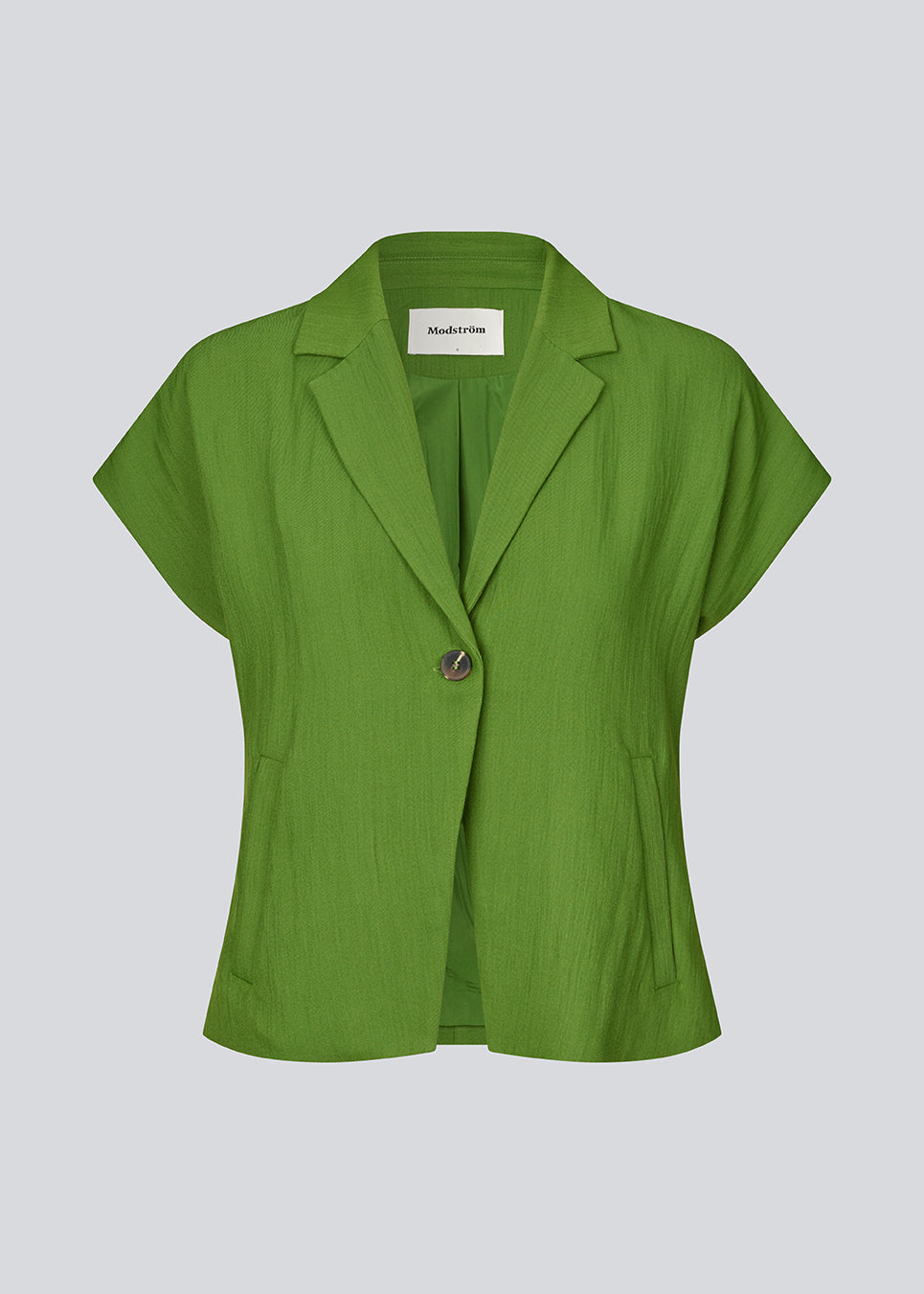 Short-sleeved blazer vest with a notched collar. The BenittaMD Vest features a relaxed, waist-focused fit, side pockets, and a single-button closure – the lightweight fabric creates a modern, effortless look, perfect worn alone or layered for a sharp, fashion-forward style.
 