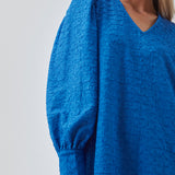 Minidress in blue with long volume sleeves a cuff. BisouMD dress has a v-neckline and an a-shaped silhouette in the body. The model is 176 cm and wears a size S/36
