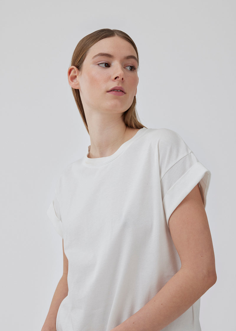 White t-shirt in organic cotton with a slightly cropped length. BrazilMD short t-shirt has a rounder neck and rolled-up sleeves. The model is 177 cm and wears a size S/36.<br>