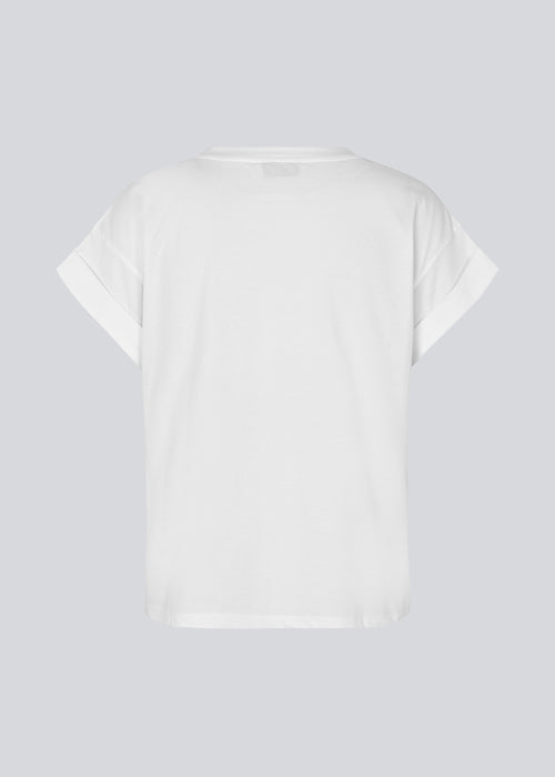 White t-shirt in organic cotton with a slightly cropped length. BrazilMD short t-shirt has a rounder neck and rolled-up sleeves. The model is 177 cm and wears a size S/36.