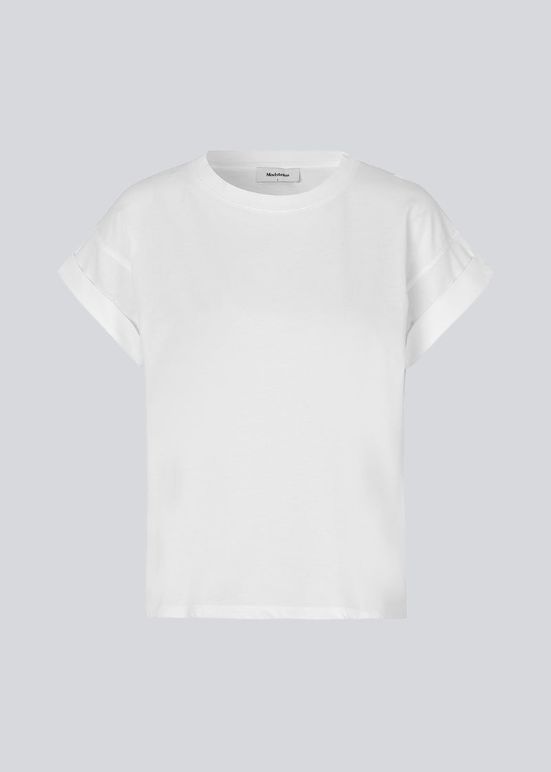 White t-shirt in organic cotton with a slightly cropped length. BrazilMD short t-shirt has a rounder neck and rolled-up sleeves. The model is 177 cm and wears a size S/36.