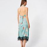 Elegant maxi dress featuring an artistic print and feminine details. Carinamd print dress is crafted from a lightweight, smooth fabric with a high halterneck neckline that fastens at the back of the neck and a self-tie belt at the waist to define the silhouette. The long, flowing fit is finished with a contrasting lace trim at the hem, adding a refined and romantic touch. A standout dress, perfect for summer parties, weddings, and other special occasions.