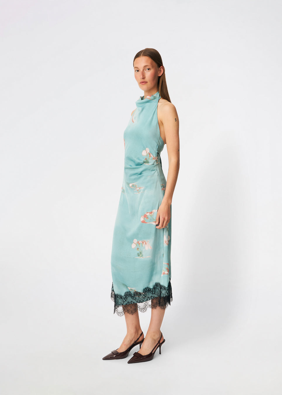 Elegant maxi dress featuring an artistic print and feminine details. Carinamd print dress is crafted from a lightweight, smooth fabric with a high halterneck neckline that fastens at the back of the neck and a self-tie belt at the waist to define the silhouette. The long, flowing fit is finished with a contrasting lace trim at the hem, adding a refined and romantic touch. A standout dress, perfect for summer parties, weddings, and other special occasions.