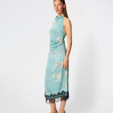 Elegant maxi dress featuring an artistic print and feminine details. Carinamd print dress is crafted from a lightweight, smooth fabric with a high halterneck neckline that fastens at the back of the neck and a self-tie belt at the waist to define the silhouette. The long, flowing fit is finished with a contrasting lace trim at the hem, adding a refined and romantic touch. A standout dress, perfect for summer parties, weddings, and other special occasions.