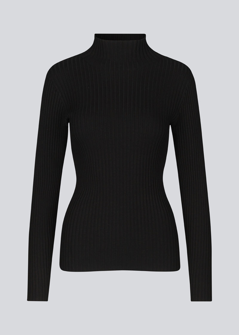 Slim fitted black long sleeved top in a stretchy rib knit with a high neck. Made from more responsible materials.  The model is 177 cm and wears a size S/36.