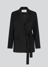 CayaMD blazer in black is designed for a relaxed fit with classic details with a twist from the tie-belt at the waist. Made from recycled materials. 