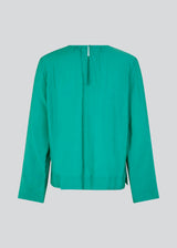 ChristopherMD top in green has a regular body with a round neck with gatherings, and small opening with button closure in the back. Long, wide sleeves. The model is 175 cm and wears a size S/36.