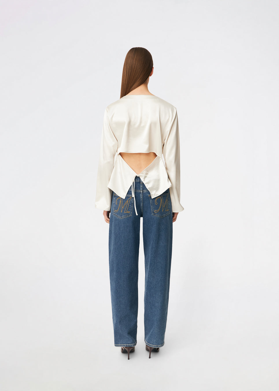 Elegant satin blouse with a feminine and contemporary look. Cianomd top is crafted from a lustrous satin fabric with long sleeves, a boat neckline, and a striking open-back detail finished with delicate tie fastening. A refined wardrobe staple that pairs effortlessly with tailored trousers, denim, or occasion-ready skirts.