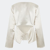 Elegant satin blouse with a feminine and contemporary look. Cianomd top is crafted from a lustrous satin fabric with long sleeves, a boat neckline, and a striking open-back detail finished with delicate tie fastening. A refined wardrobe staple that pairs effortlessly with tailored trousers, denim, or occasion-ready skirts.