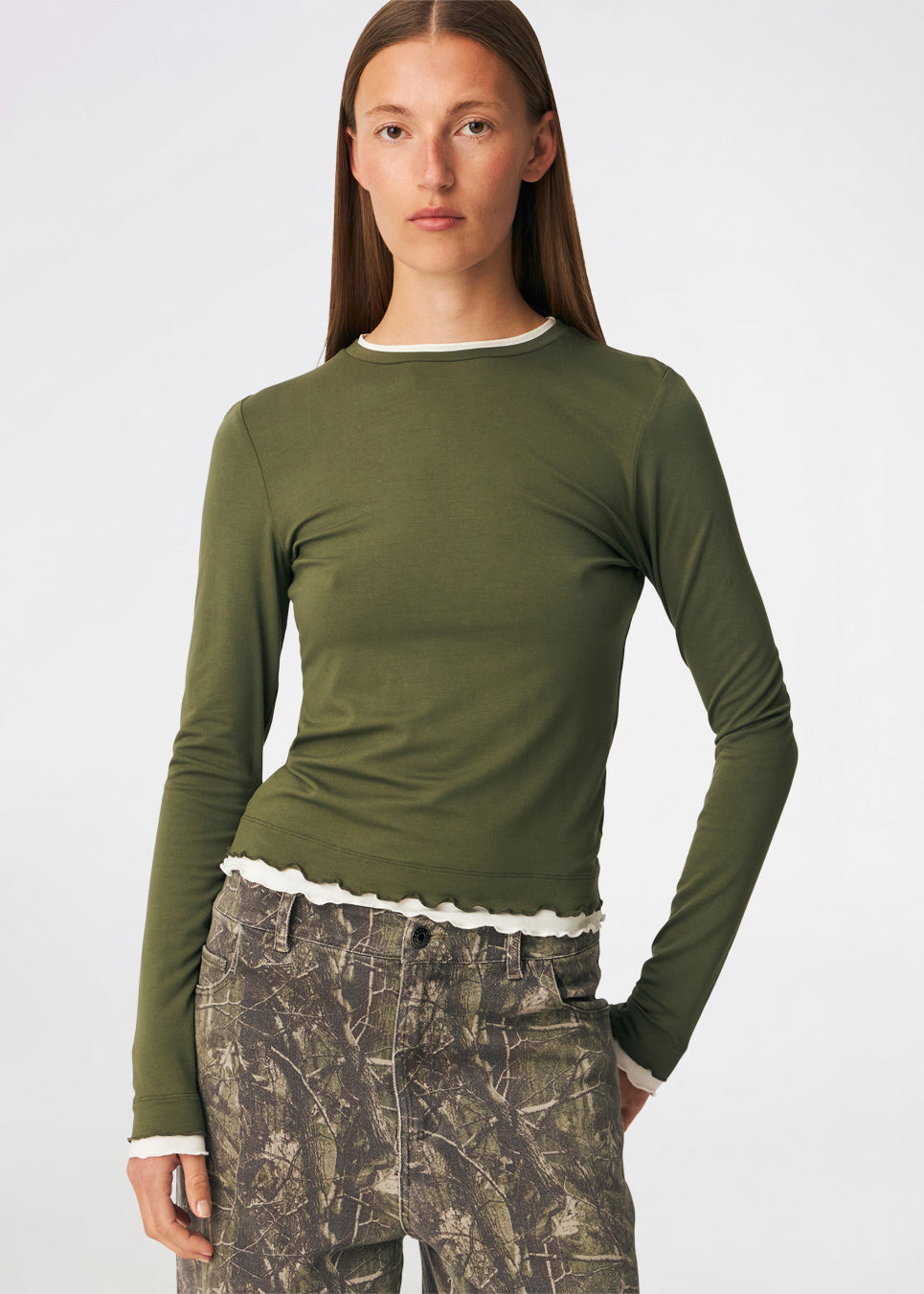 Long-sleeved T-shirt crafted from a soft and comfortable fabric. CiljaMD LS T-shirt features a fitted silhouette with a crew neckline and contrasting trims at the neckline, cuffs, and hem, creating a layered look. The delicate lettuce-edge finish adds a feminine touch, making it perfect to wear on its own or layered under knitwear, shirts, or jackets.