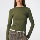 Long-sleeved T-shirt crafted from a soft and comfortable fabric. CiljaMD LS T-shirt features a fitted silhouette with a crew neckline and contrasting trims at the neckline, cuffs, and hem, creating a layered look. The delicate lettuce-edge finish adds a feminine touch, making it perfect to wear on its own or layered under knitwear, shirts, or jackets.
