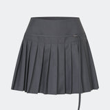 Pleated mini skirt with a modern, preppy aesthetic. Cirkelinemd skirt features a low-rise waist with a wrap-inspired design, decorative strap detail, and crisp pleats that create beautiful movement and volume. The mini length and tailored silhouette make it a versatile piece for both everyday styling and more elevated occasions. Pair it with a shirt, knitwear, or a simple top for a timeless look.