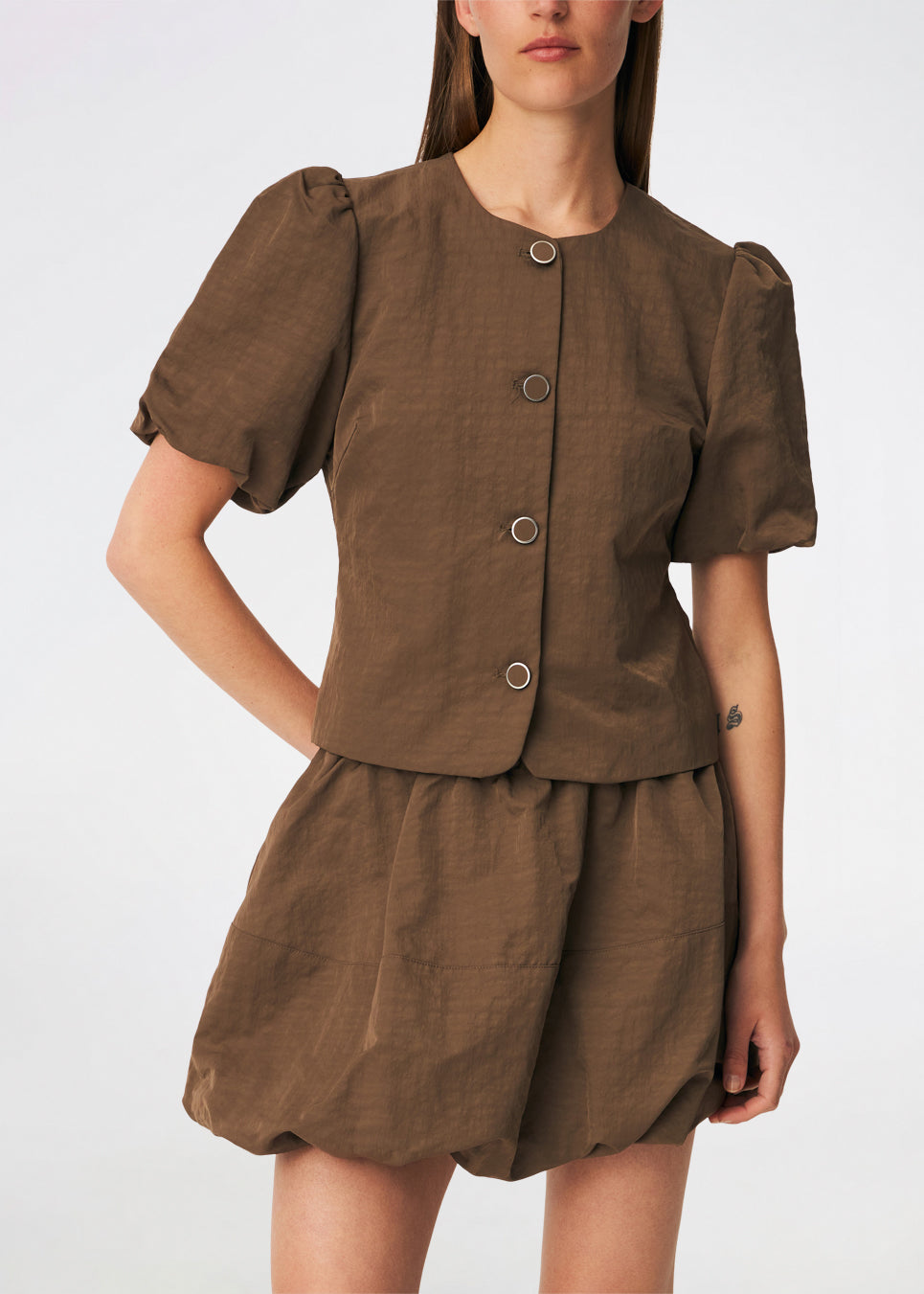 Short-sleeved blazer with a feminine, tailored silhouette. The CirkelMD SS Blazer features a round neckline, short voluminous puff sleeves, and decorative front button closure. Crafted in a lightly textured fabric, it can be worn as both a top and a lightweight jacket, making it ideal for special occasions or an elevated everyday look.