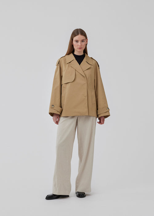 Short trench coat in beige in a cotton quality with concealed buttons down the front. Clara jacket has an oversized silhouette and classic details. Lined.
