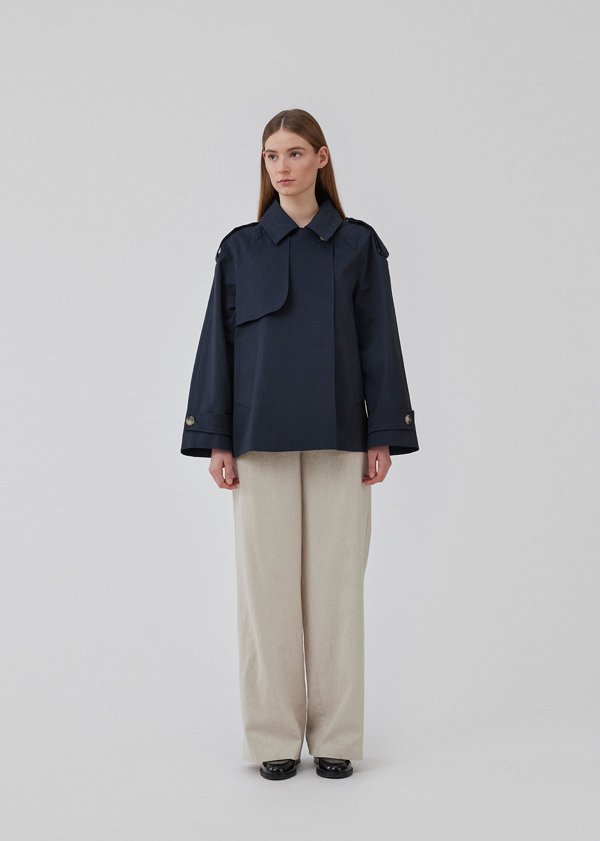 Short trench coat in dar blue in a cotton quality with concealed buttons down the front. Clara jacket has an oversized silhouette and classic details. Lined.