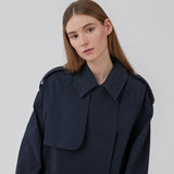 Short trench coat in dar blue in a cotton quality with concealed buttons down the front. Clara jacket has an oversized silhouette and classic details. Lined.