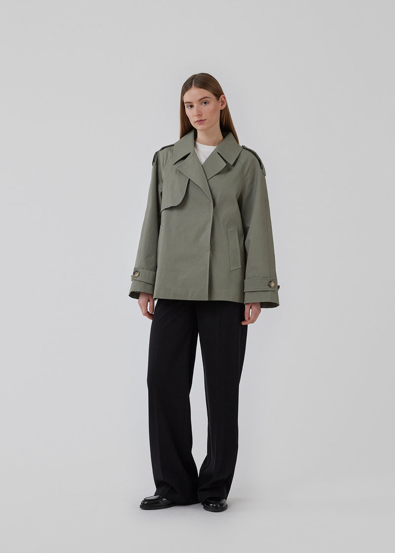 Short trench coat in soft green in a cotton quality with concealed buttons down the front. Clara jacket has an oversized silhouette and classic details. Lined. 