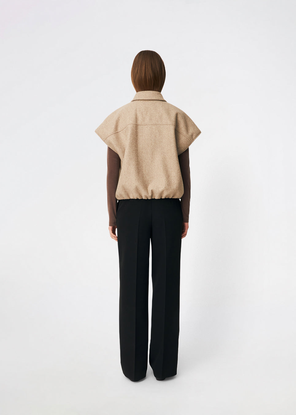 Short vest with a modern, relaxed aesthetic. Cleamd vest features a boxy silhouette with short, wide sleeves, a classic collar, and snap button closure at the front. Discreet front pockets and an elasticated hem create a soft, rounded shape and a comfortable fit. Perfect for layering over knitwear, shirts, or dresses during the transitional seasons.