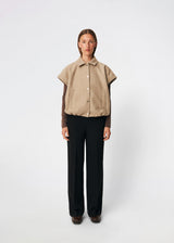 Short vest with a modern, relaxed aesthetic. Cleamd vest features a boxy silhouette with short, wide sleeves, a classic collar, and snap button closure at the front. Discreet front pockets and an elasticated hem create a soft, rounded shape and a comfortable fit. Perfect for layering over knitwear, shirts, or dresses during the transitional seasons.