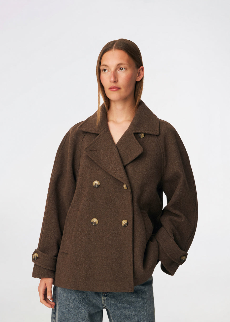 Short double-breasted wool-blend jacket with a wide lapel collar, buttoned cuff straps and raglan sleeves that create a rounded shoulder line. Wear it with denim or a fluid skirt. The model is 175 cm tall and is wearing a size S/36.