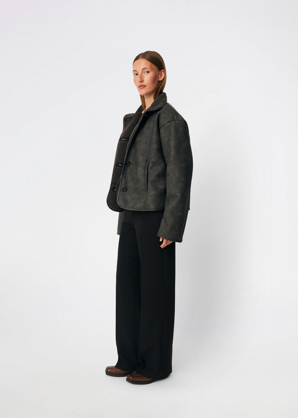 Short faux shearling jacket with a modern, timeless aesthetic. Coralinemd jacket features a relaxed silhouette with a high stand collar, front button closure, and decorative seam detailing that enhances its classic design. Soft teddy trims at the cuffs add warmth and contrast, while the slightly oversized fit makes it perfect for layering throughout the colder months.