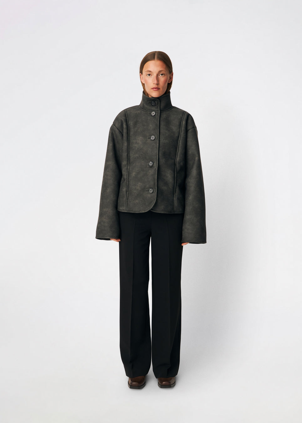 Short faux shearling jacket with a modern, timeless aesthetic. Coralinemd jacket features a relaxed silhouette with a high stand collar, front button closure, and decorative seam detailing that enhances its classic design. Soft teddy trims at the cuffs add warmth and contrast, while the slightly oversized fit makes it perfect for layering throughout the colder months.