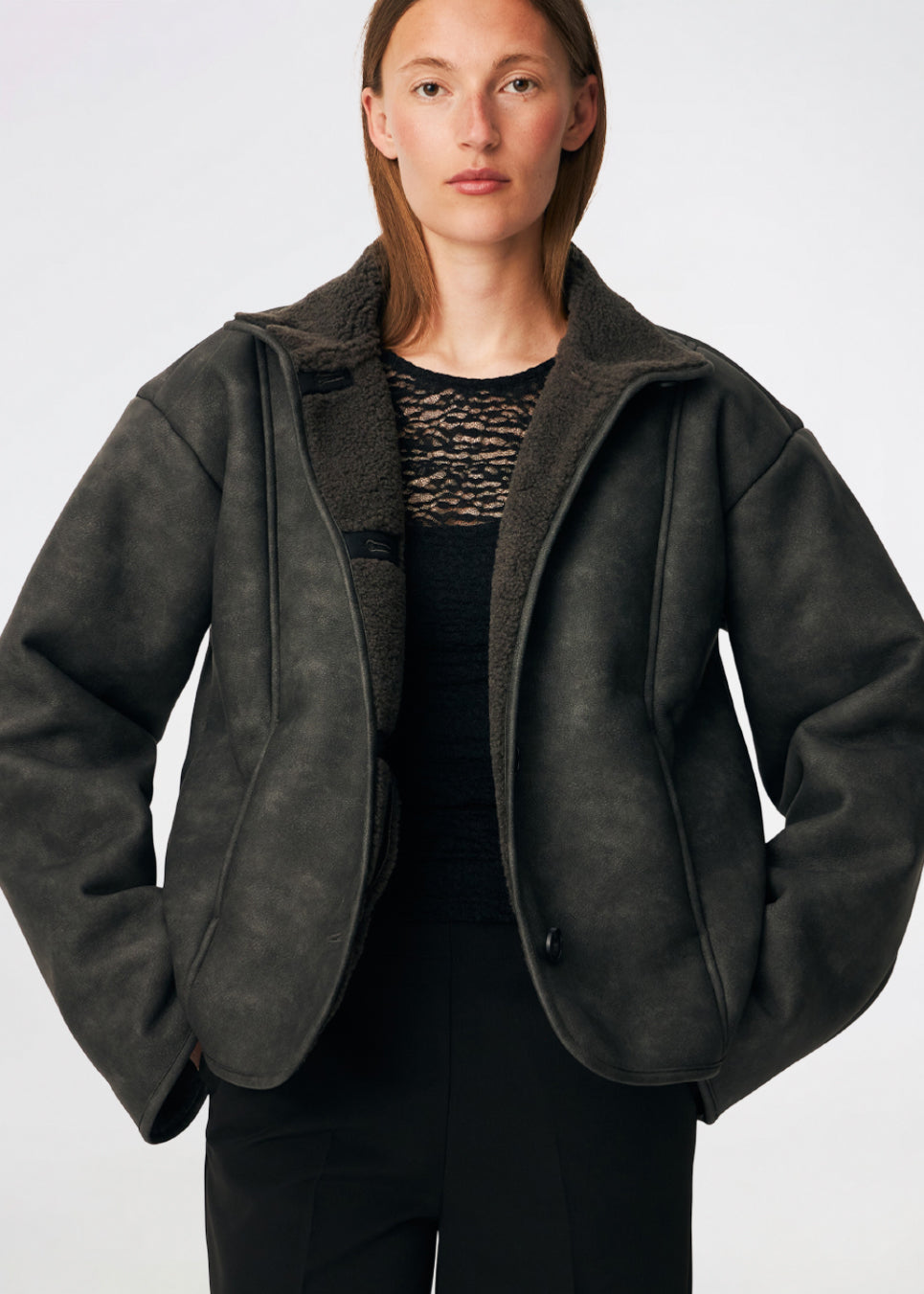 Short faux shearling jacket with a modern, timeless aesthetic. Coralinemd jacket features a relaxed silhouette with a high stand collar, front button closure, and decorative seam detailing that enhances its classic design. Soft teddy trims at the cuffs add warmth and contrast, while the slightly oversized fit makes it perfect for layering throughout the colder months.