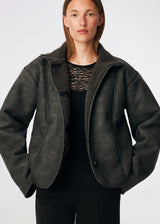 Short faux shearling jacket with a modern, timeless aesthetic. Coralinemd jacket features a relaxed silhouette with a high stand collar, front button closure, and decorative seam detailing that enhances its classic design. Soft teddy trims at the cuffs add warmth and contrast, while the slightly oversized fit makes it perfect for layering throughout the colder months.