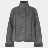 Short faux shearling jacket with a modern, timeless aesthetic. Coralinemd jacket features a relaxed silhouette with a high stand collar, front button closure, and decorative seam detailing that enhances its classic design. Soft teddy trims at the cuffs add warmth and contrast, while the slightly oversized fit makes it perfect for layering throughout the colder months.