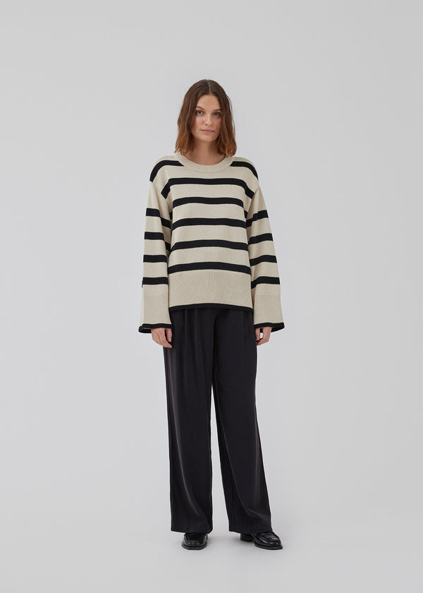 Fine-knitted oversized jumper knitted from cotton with black stripes. CorbinMD stripe o-neck has a ribbed round neckline, long wide sleeves, and wide ribbing at cuffs and hem.