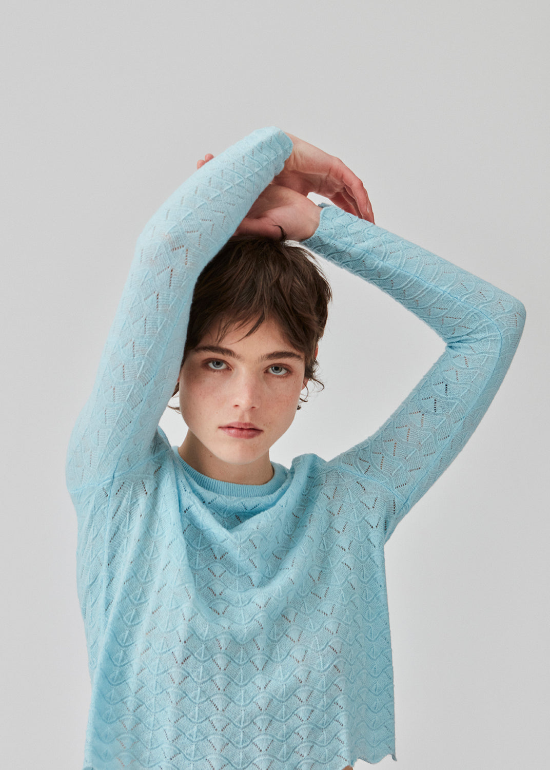 Knitted top in light blue with eyelet pattern in a light quality with wool. CordellMD short o-neck has a relaxed and cropped fit with long sleeves with wavy trims. The model is 175 cm and wears a size