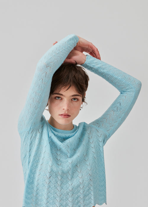 Knitted top in light blue with eyelet pattern in a light quality with wool. CordellMD short o-neck has a relaxed and cropped fit with long sleeves with wavy trims. The model is 175 cm and wears a size