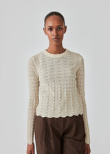 Knitted top in summer sand with eyelet pattern in a light quality with wool. CordellMD short o-neck has a relaxed and cropped fit with long sleeves with wavy trims. The model is 175 cm and wears a size S/36.