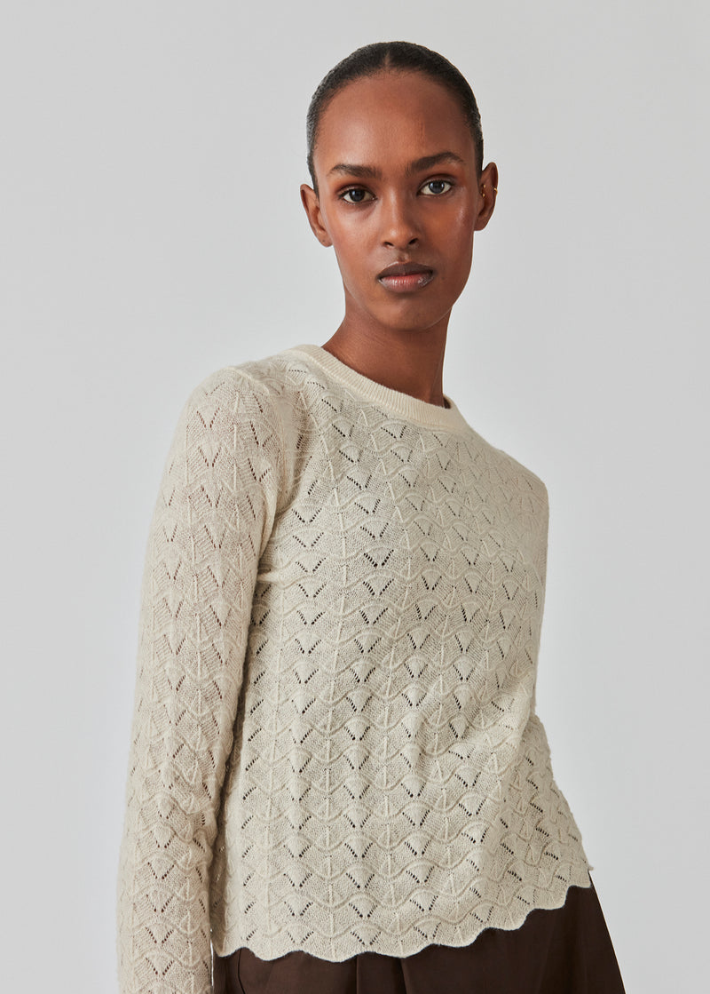 Knitted top in summer sand with eyelet pattern in a light quality with wool. CordellMD short o-neck has a relaxed and cropped fit with long sleeves with wavy trims. The model is 175 cm and wears a size S/36.'